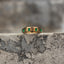 Gold-tone spinner ring set with square emerald-green zircon stones shown from the front