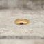 Gold-tone band ring with a red marquise stone shown from the front