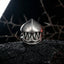Front view of the gothic monster teeth ring with dramatic fang design placed on cracked dark rock in shadowy gothic setting