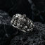 Detailed close-up of the gothic skull crown ring featuring a central crowned skull surrounded by cluster skulls on dark textured rock