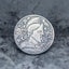 Close-up of a coin engraved with a Roman centurion profile in a Corinthian helmet with nose guard and decorative foliage crest, KC mark, Liberty inscription, dated 1936, on dark stone