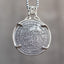 Coin pendant engraved with a skeleton pirate captain holding a lantern beside a ship sail, dated 1921, set in a four-prong bezel on a box chain
