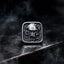 Square signet ring with skull centerpiece surrounded by octopus tentacles — oxidized silver relief on dark gothic signet face, wet black stone surface