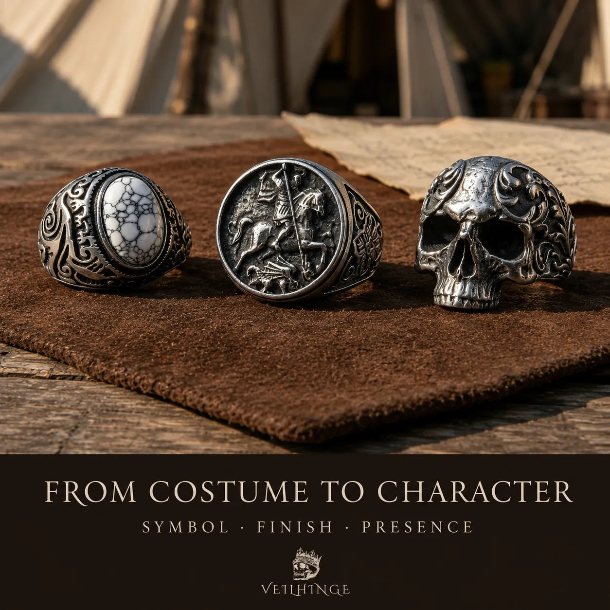 White spiderweb-stone ring, mounted-knight signet and ornate skull ring displayed on brown suede at a medieval fair jewelry stall.