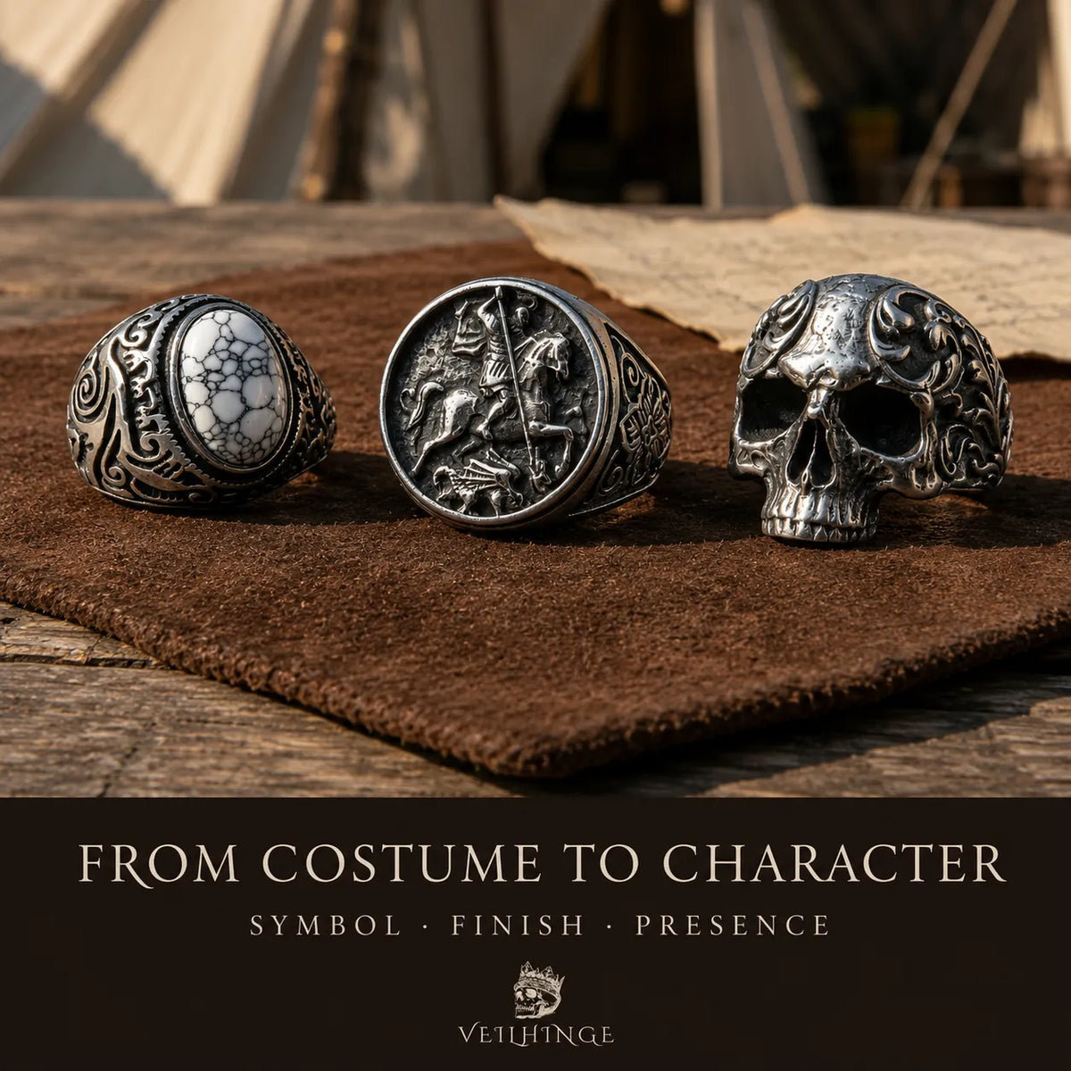 White spiderweb-stone ring, mounted-knight signet and ornate skull ring displayed on brown suede at a medieval fair jewelry stall.