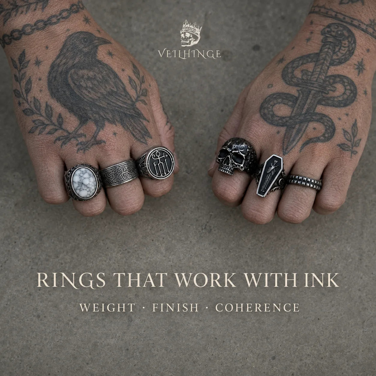 Two tattooed hands wearing oxidized silver signet, skull, stone and textured rings against a warm gray concrete background.