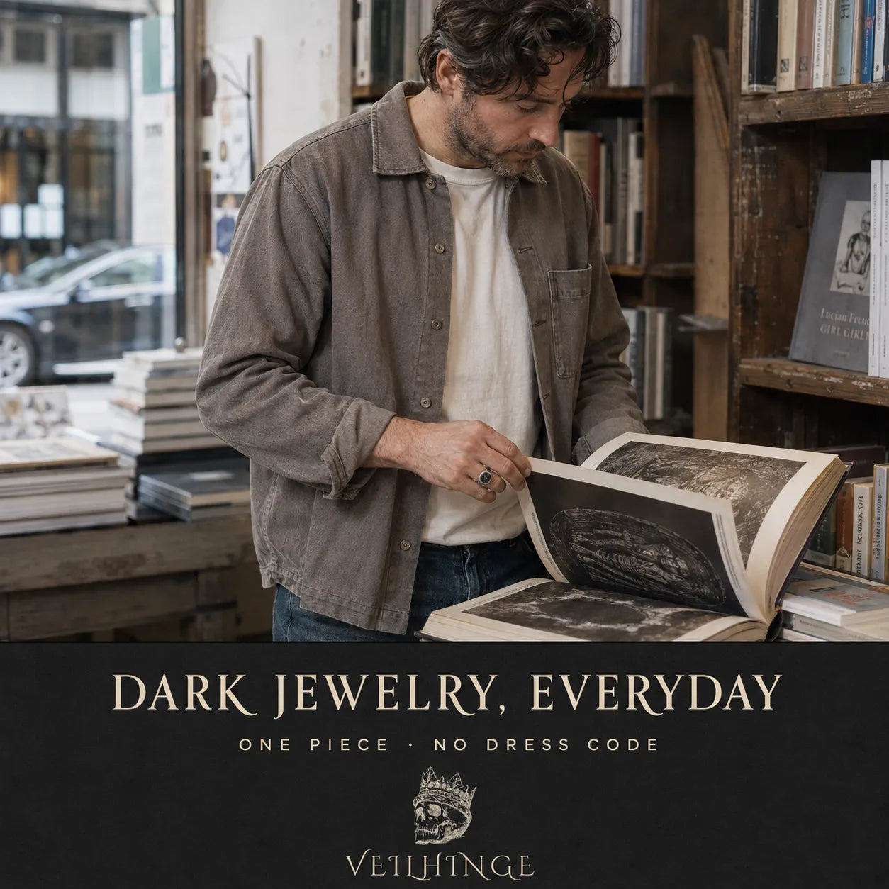 Man wearing a single oxidized silver signet ring while browsing an art book in an independent bookshop.