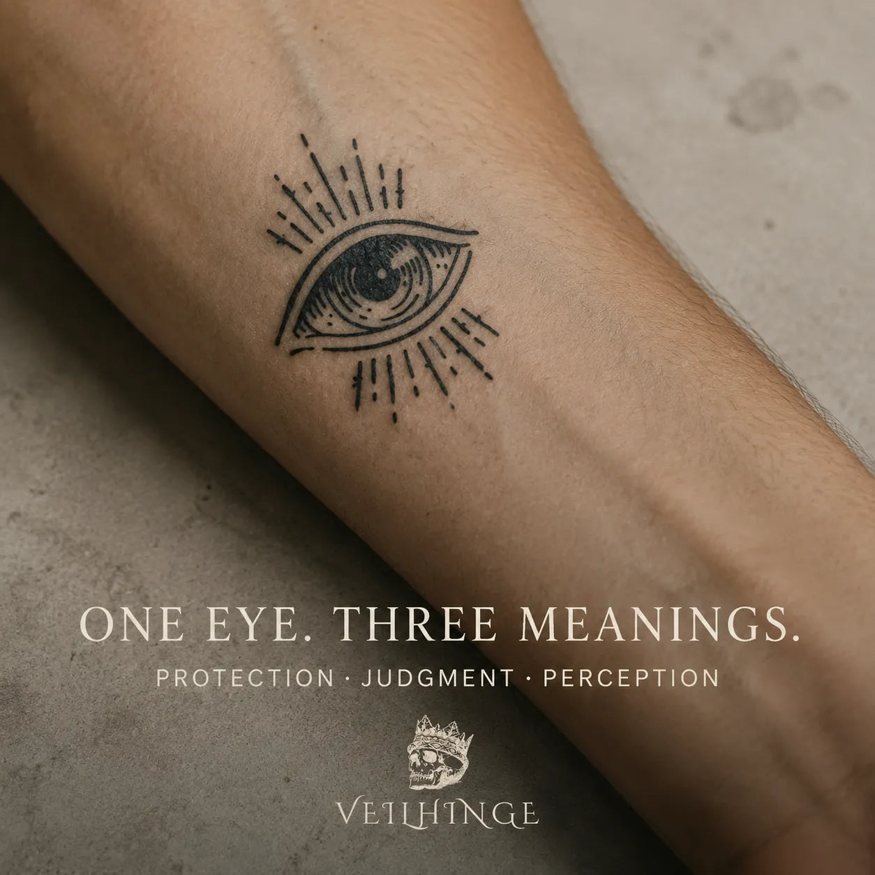 Minimal black eye tattoo with radiating lines on a naturally textured forearm resting against warm gray stone.