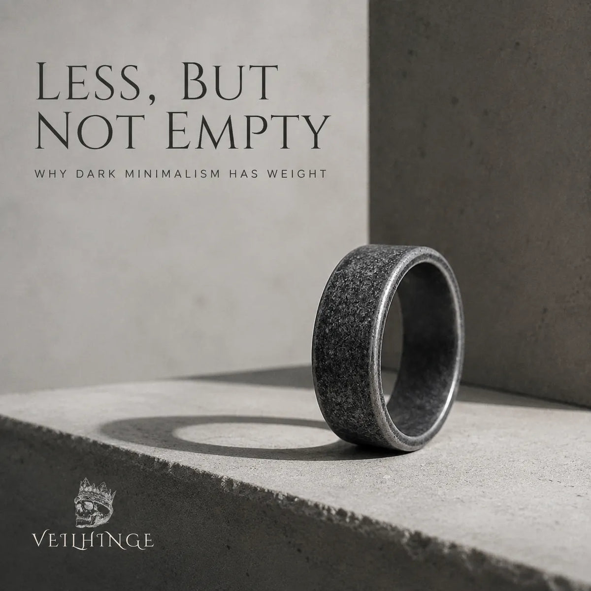 Wide oxidized minimalist ring with a textured dark surface standing in a restrained concrete architectural setting.