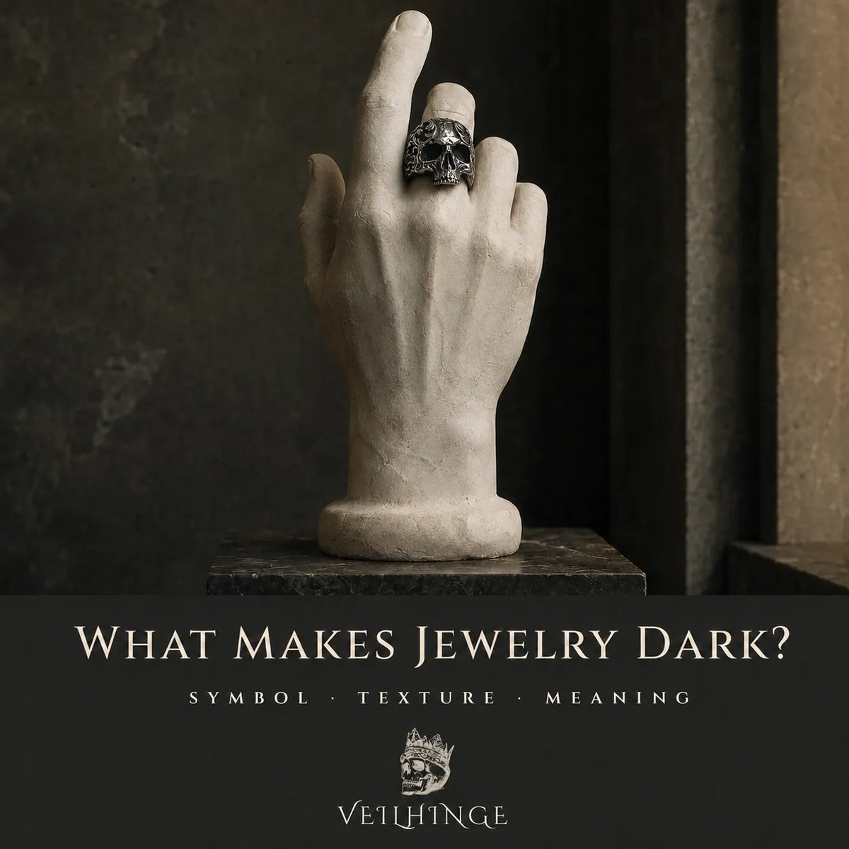 Ivory plaster hand wearing an oxidized silver skull ring with Baroque scrollwork in a museum-style display.