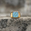 Front view of an 18K gold-plated signet ring with a light blue woven inlay