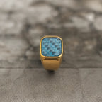 Upright front view of the polished 18K gold-plated signet ring with blue woven inlay