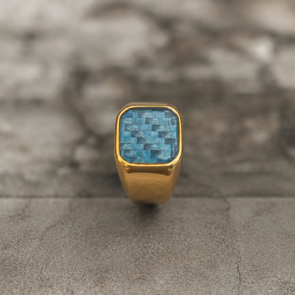 Upright front view of the polished 18K gold-plated signet ring with blue woven inlay