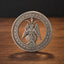A circular silver-toned coin or medallion featuring a winged goat-headed figure seated in the center, with the text 'E PLURIBUS UNUM' around the edge and '1893' at the bottom, displayed upright on a wooden surface against a dark background.
