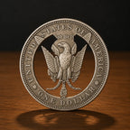 A detailed silver-colored commemorative coin featuring an eagle emblem and the text 'UNITED STATES OF AMERICA' and 'ONE DOLLAR', standing upright on a wooden surface against a dark background.