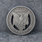 A silver-colored United States one dollar coin featuring an eagle design, photographed against a textured gray concrete background.
