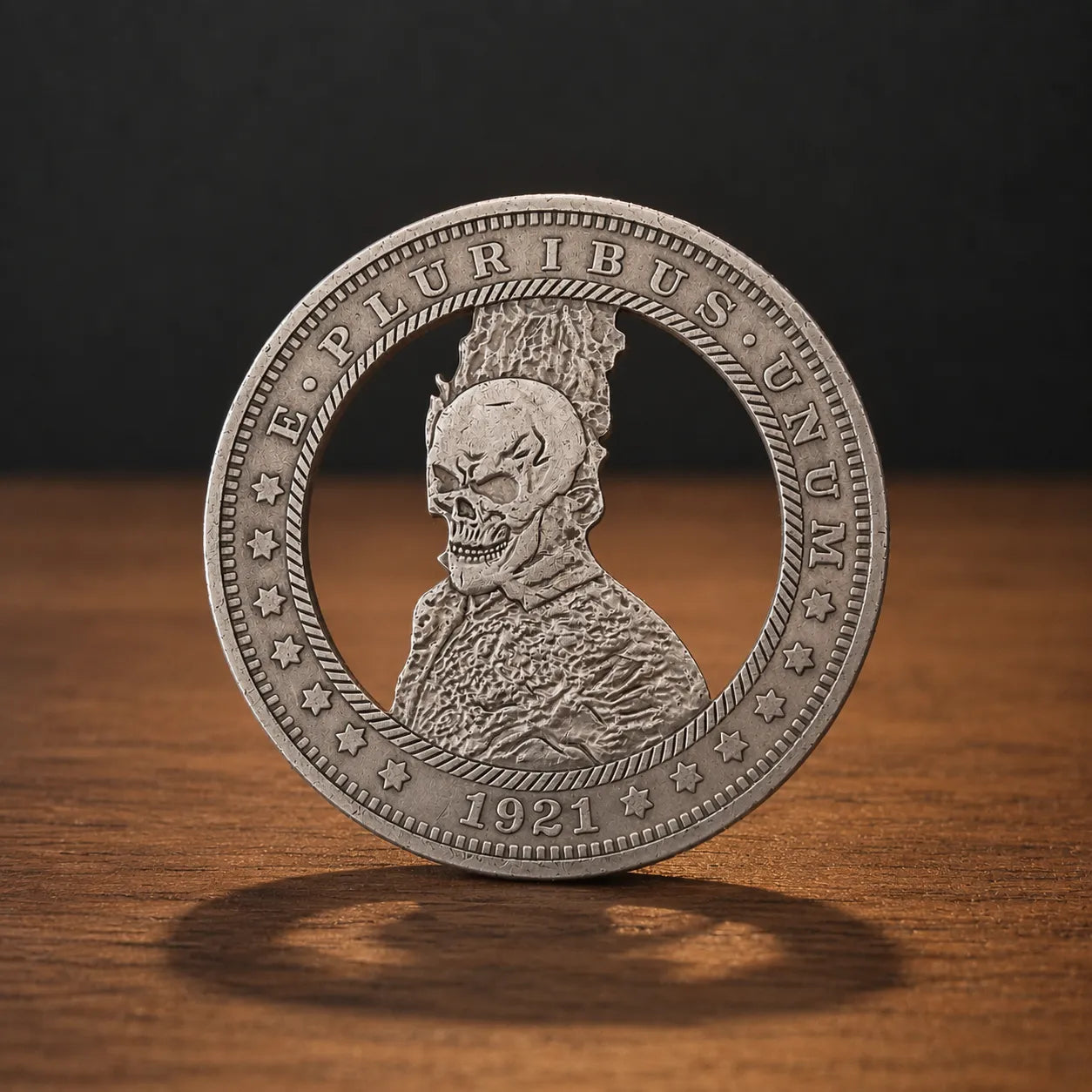 A silver-colored commemorative coin featuring a detailed profile of a skull wearing a crown, with the text 'E. PLURIBUS UNUM' and '1921' on a wooden surface against a dark background.