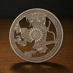 A round silver-toned metal coin or medallion featuring an engraved zodiac wheel design with a central sun face and cutout figures, displayed upright on a wooden surface against a dark background.