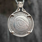 Coin pendant engraved with a large all-seeing eye with iris detail and concentric ripple rings filling the entire face, dated 1881, set in a four-prong bezel on a chain