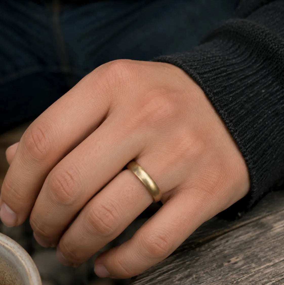 Close-up of an antique gold-tone plain band ring worn in a casual café setting