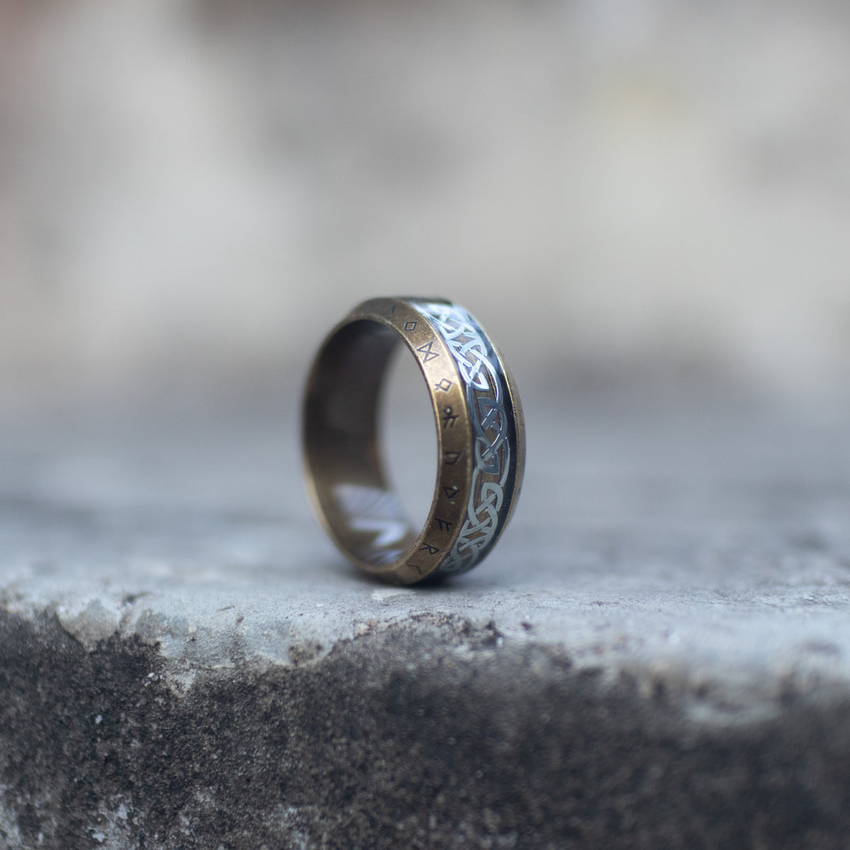 Side view of an antique gold-tone Viking ring engraved with runes and Celtic knots
