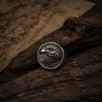 Antique silver eagle head signet ring resting on a dark wood surface, showing the raised bald eagle engraving detail with oxidized shadow in the feather and eye recesses