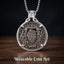 baroque coat of arms coin pendant — heraldic shield with flanking figures engraved on replica coin in open circular silver frame, skull bail on box chain