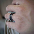 Wide black band ring with layered dragon scale texture worn on a middle finger, matte black finish with raised scale pattern visible from a side angle