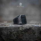 black oxidized square ring side profile — brushed linear texture across the face, angular silhouette on stone edge