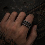 Wide oxidized silver ring with bone spine motif worn on a man's hand against a dark textured background