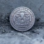 Close-up of a coin engraved with a horned bull skull, Eye of Providence above, spread wings on either side, rose motifs below, E Pluribus Unum border, dated 1921