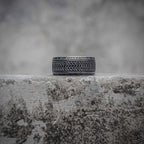 Celtic knot band ring with dense braid weave engraving and Elder Futhark rune border in oxidized black stainless steel, dark aesthetic Viking ring by Veilhinge, front view