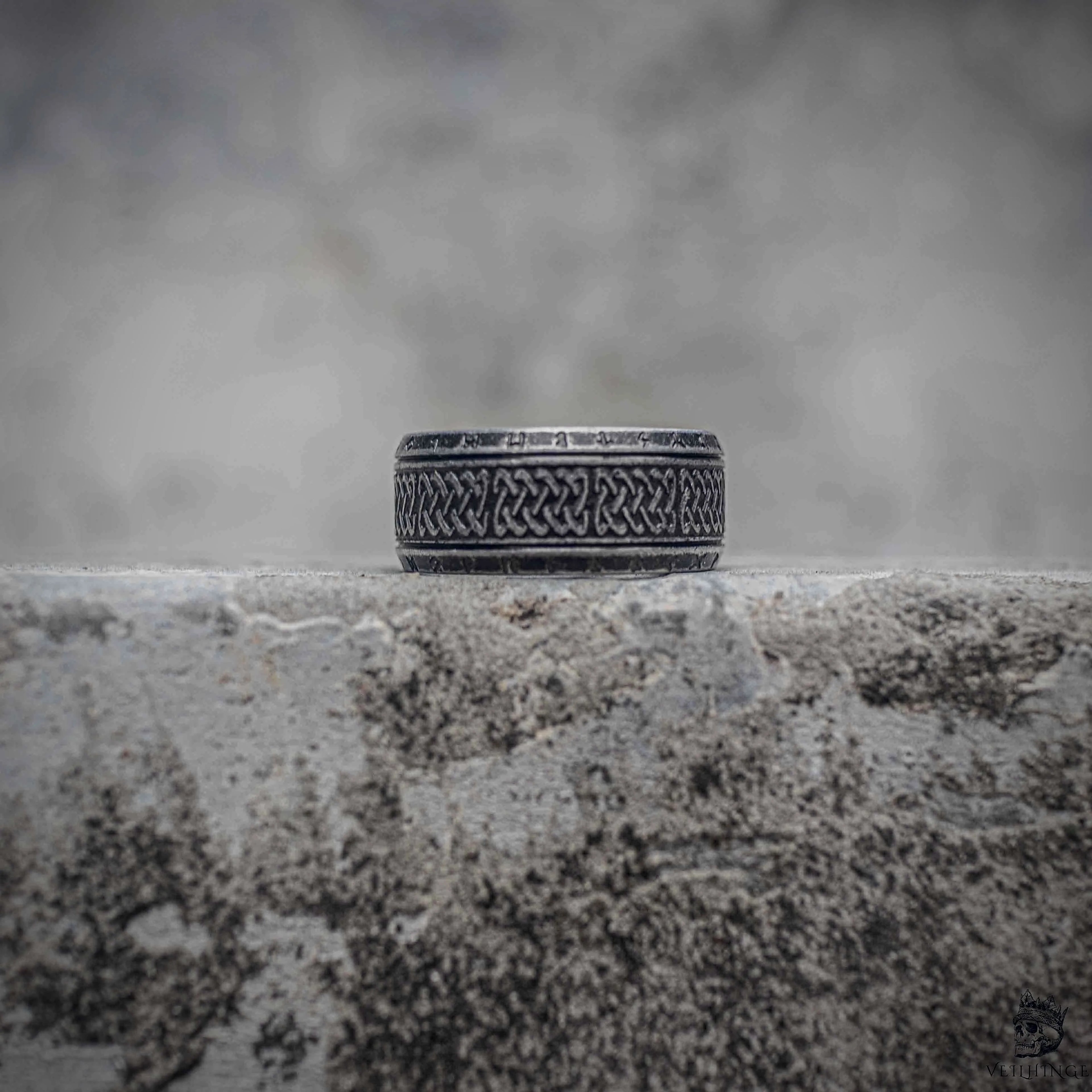 Celtic knot band ring with dense braid weave engraving and Elder Futhark rune border in oxidized black stainless steel, dark aesthetic Viking ring by Veilhinge, front view