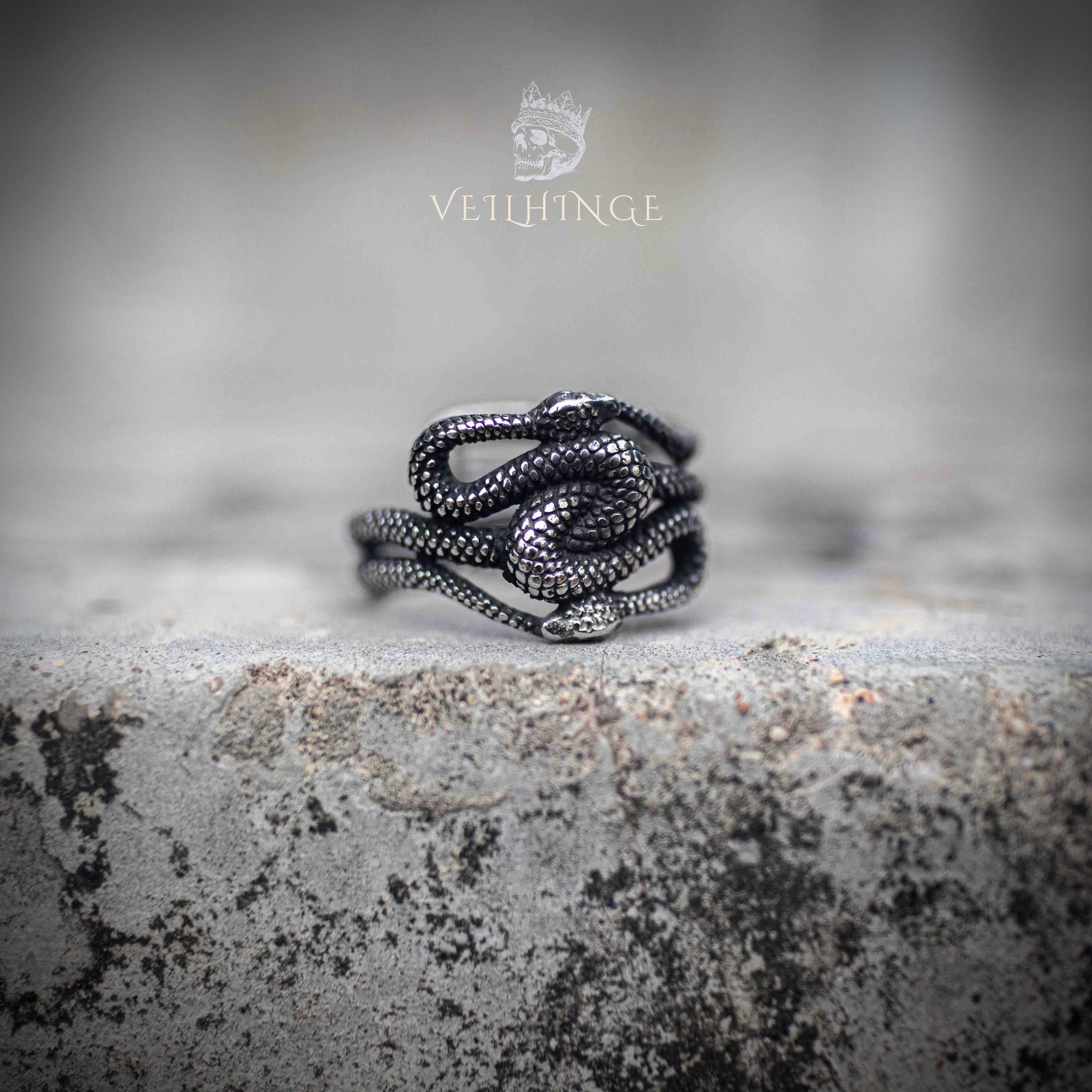 Open adjustable ring with multiple coiled snakes intertwined — oxidized dark silver finish, serpent bodies layered across the band, front view on stone Main image