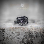 Open adjustable ring with multiple coiled snakes intertwined — oxidized dark silver finish, serpent bodies layered across the band, front view on stone
