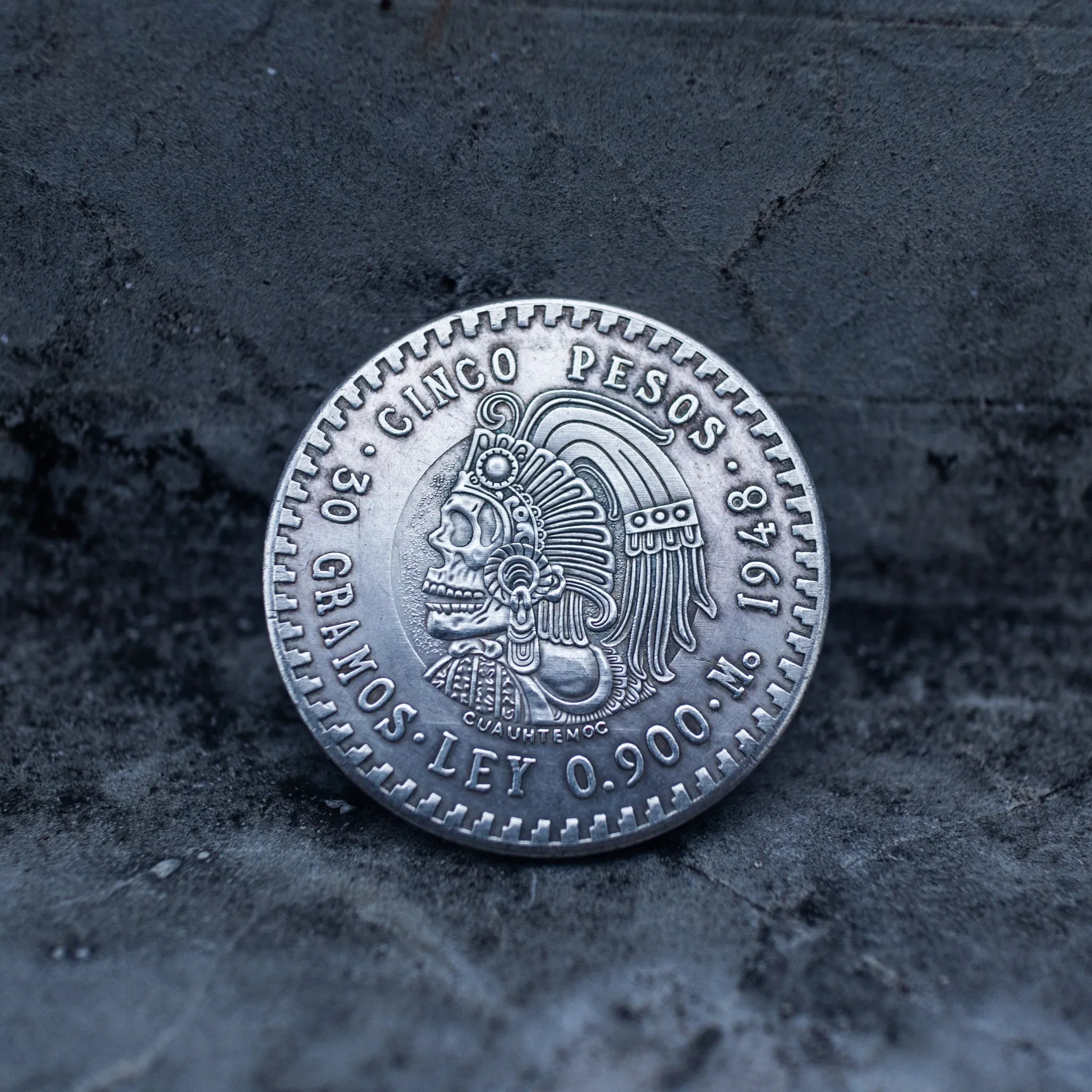 Cinco Pesos coin obverse showing a skull-faced Cuauhtémoc wearing an elaborate Aztec feather headdress, Ley 0.900 and 30 Gramos inscriptions visible