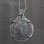 Coin pendant engraved with a skeleton couple dancing — a top-hatted gentleman skeleton leading a long-skirted female skeleton in a backbend, dated 1879, set in a four-prong bezel on a chain