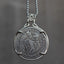 Coin pendant engraved with a skeleton couple dancing — a top-hatted gentleman skeleton leading a long-skirted female skeleton in a backbend, dated 1879, set in a four-prong bezel on a chain