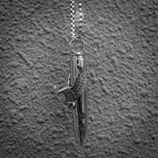 eagle wing bullet pendant close-up — spread wing motif gripping polished bullet casing, biker dark aesthetic necklace
