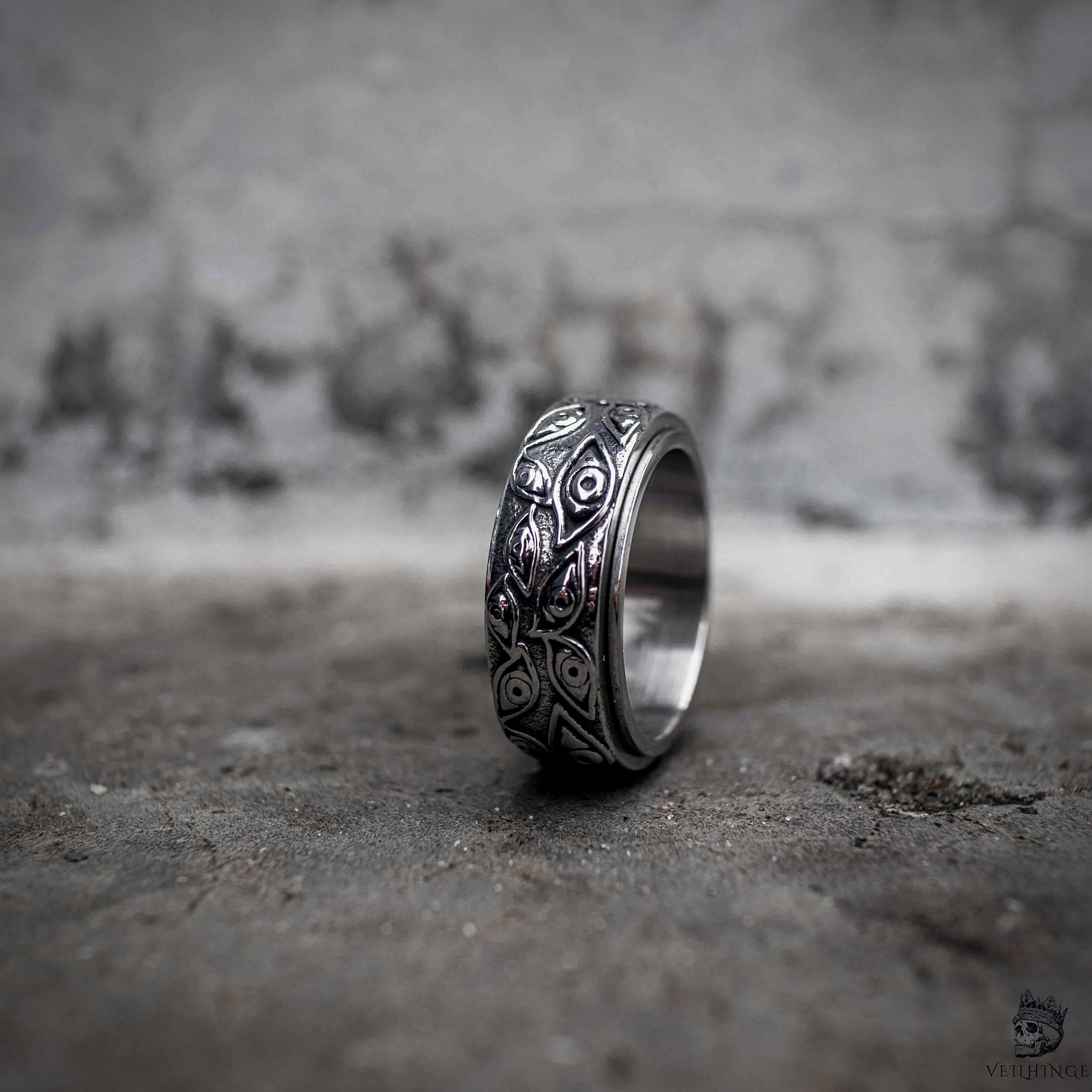 Evil eye spinner ring with rotating oxidized silver band engraved with all-seeing eye pattern, dark aesthetic stainless steel anxiety ring by Veilhinge, upright view
