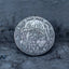 Close-up of a coin engraved with the Evil Queen witch in hooded cloak, poison apple visible at lower right, dated 1964