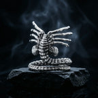 Detailed studio shot of the Facehugger Xenomorph ring on dark stone with atmospheric smoke