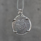 Coin pendant engraved with four skulls arranged around an anchor bearing a Carpe Diem banner, radiant rays, E Pluribus Unum border, dated 1896, set in a four-prong bezel on a chain