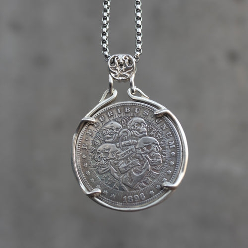 Coin pendant engraved with four skulls arranged around an anchor bearing a Carpe Diem banner, radiant rays, E Pluribus Unum border, dated 1896, set in a four-prong bezel on a chain