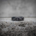 Geometric diamond faceted band ring with sandblasted oxidized black surface and polished cut lines in stainless steel, minimalist dark aesthetic ring by Veilhinge, front view