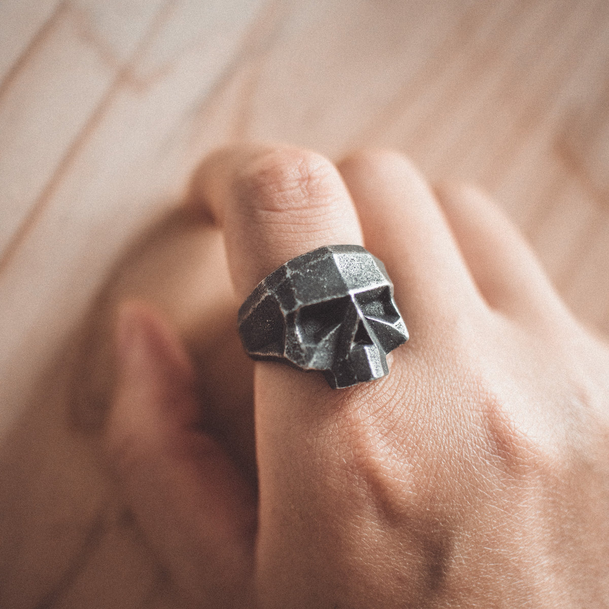 Close-up of the VEILHINGE Geometric Skull Ring worn on hand, showing the faceted low-poly skull design and oxidized finish.