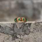Gold-tone spinner ring set with square emerald-green zircon stones shown from the front