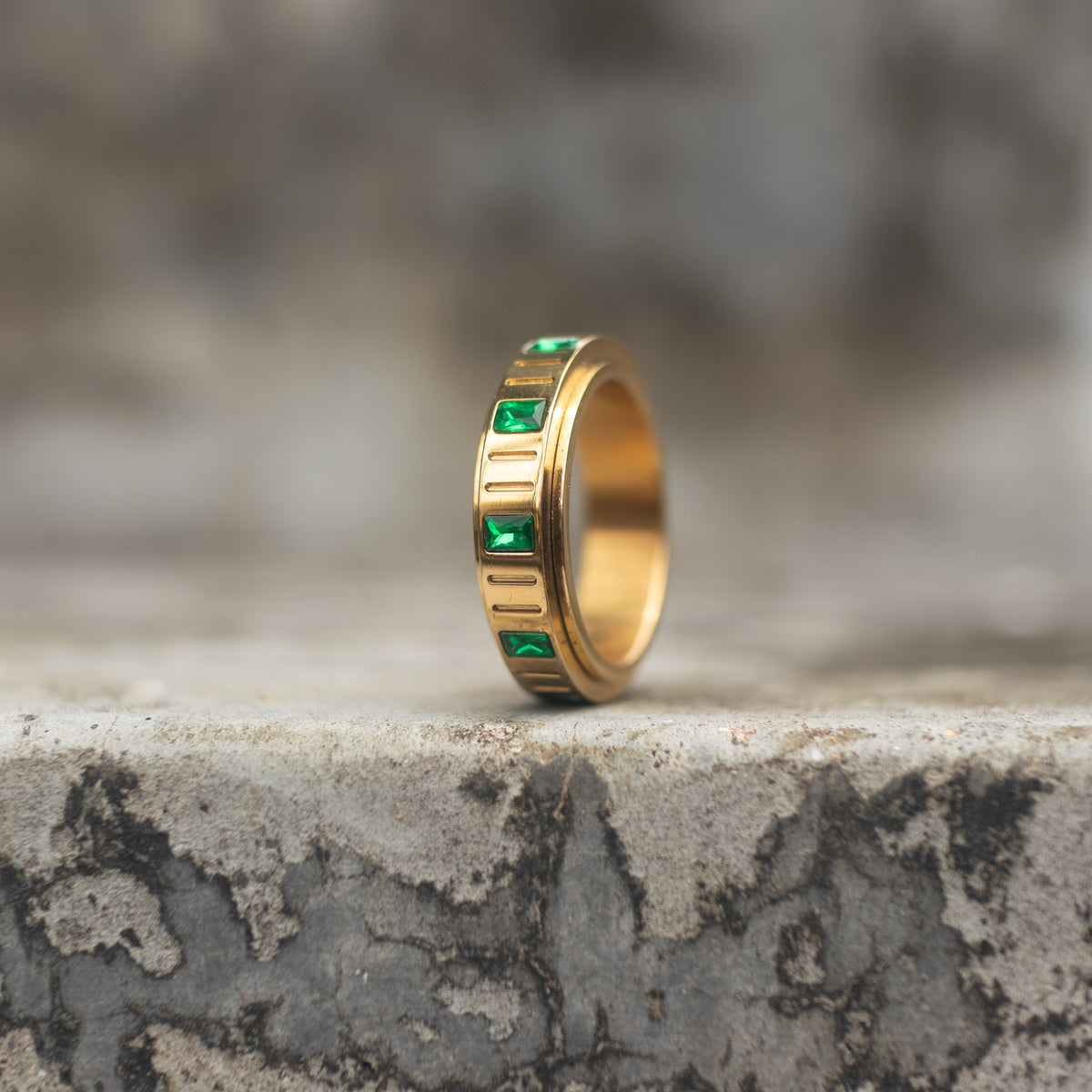 Gold-tone spinner ring with square emerald-green zircon stones shown upright