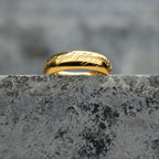 Close-up of the engraved script and mirror-polished finish on a gold-tone band ring