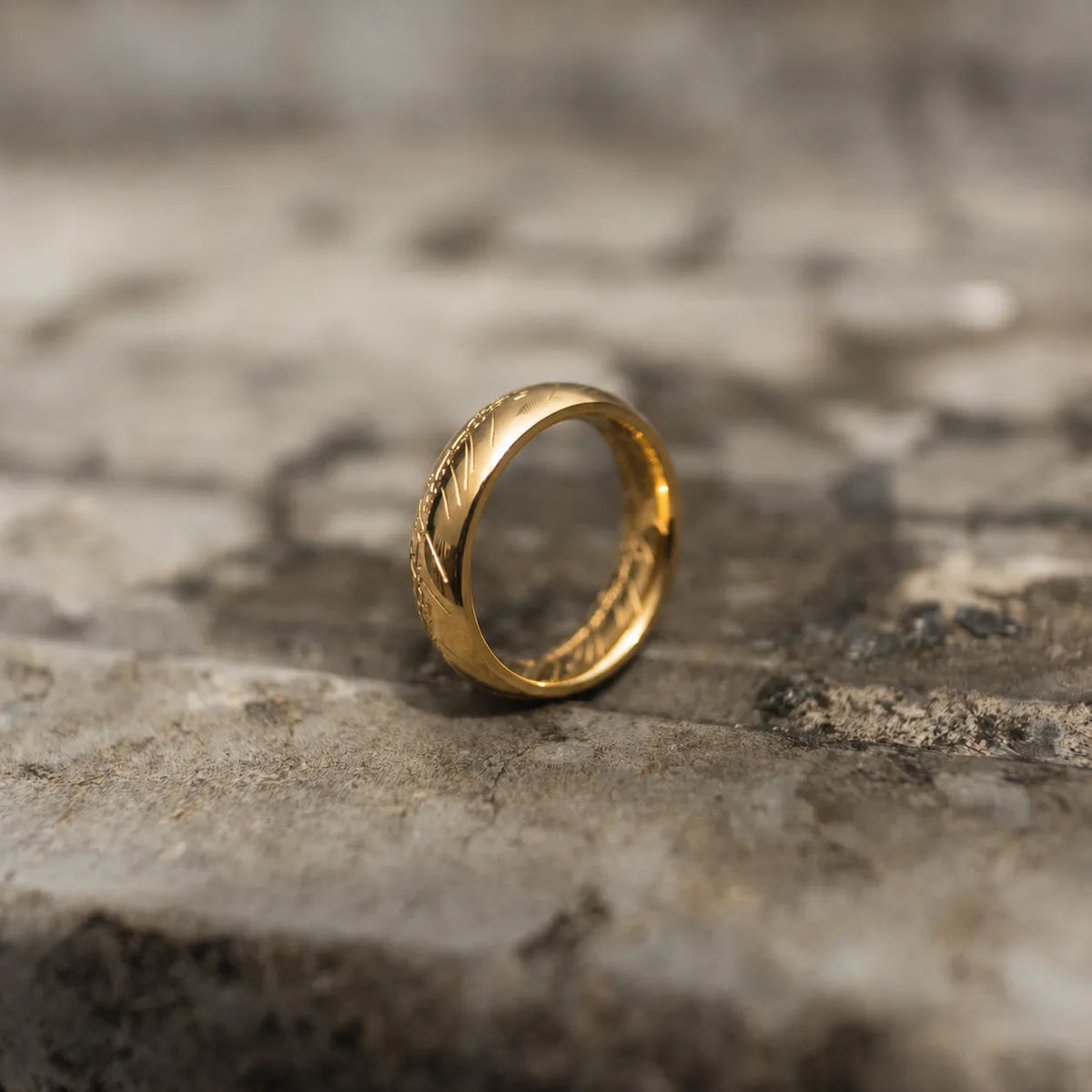 Highly polished gold-tone band ring with engraved script shown from the front